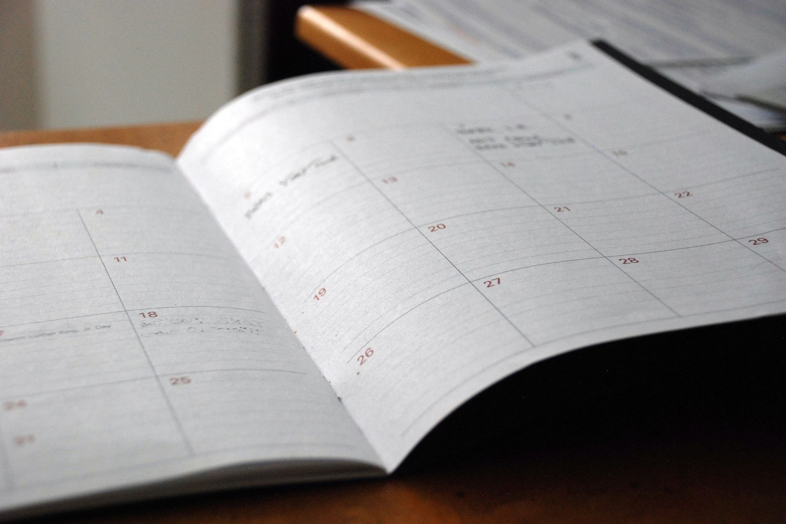 Un agenda mensuel ouvert sur un bureau en bois.