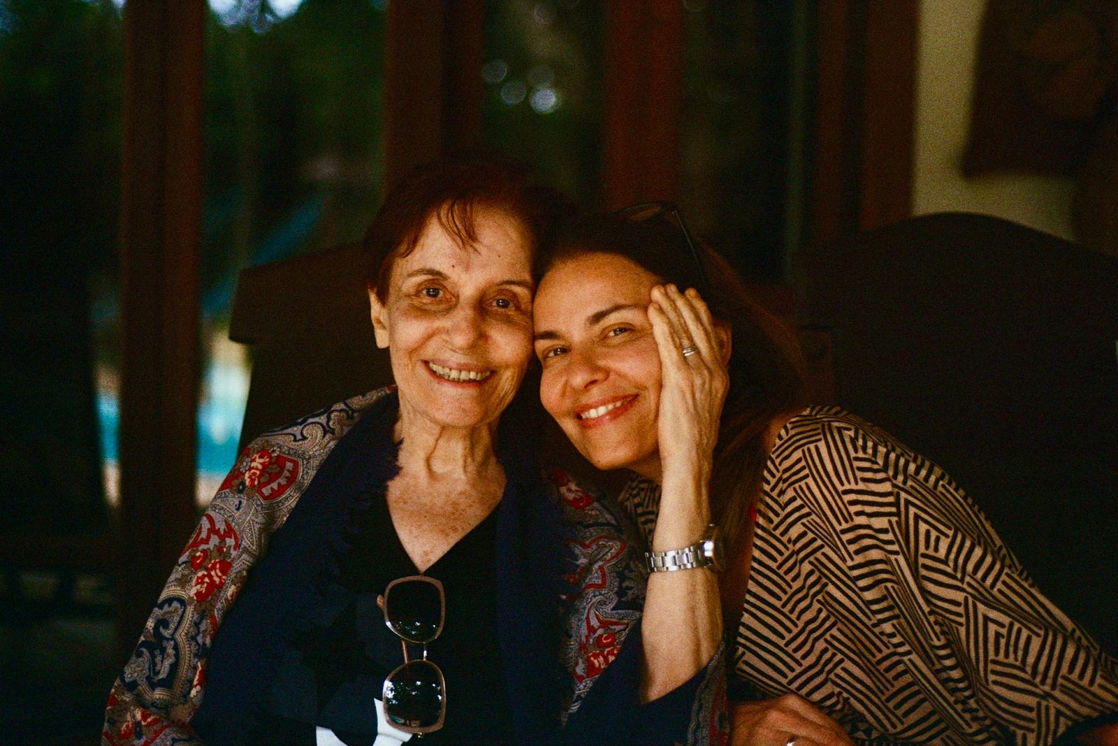 Une femme adulte et sa mère âgée, joue contre joue, sourient ensemble.
